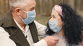 Man and women wearing medical masks looking into each other's eyes.